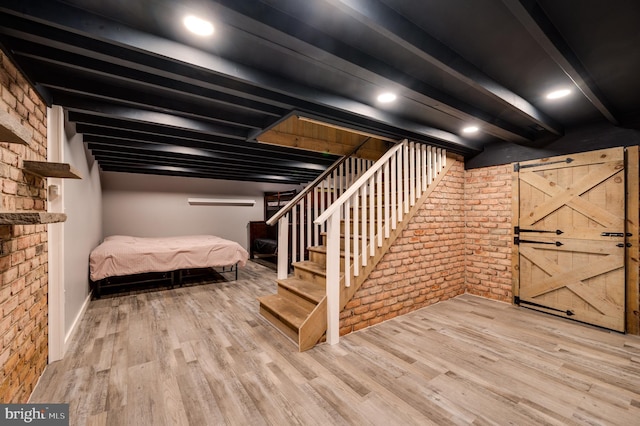 finished below grade area with brick wall and wood finished floors