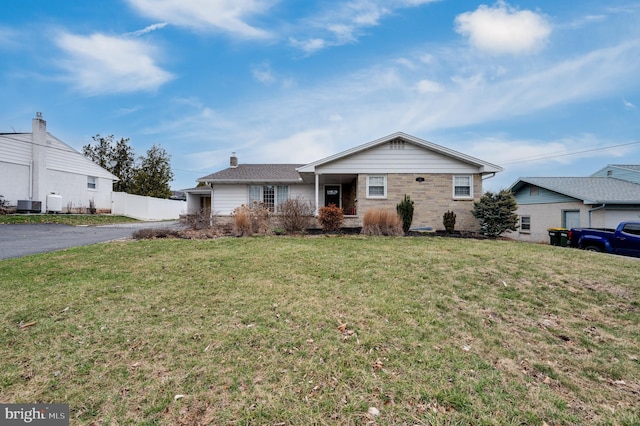 ranch-style house featuring aphalt driveway, a front lawn, central AC, and fence