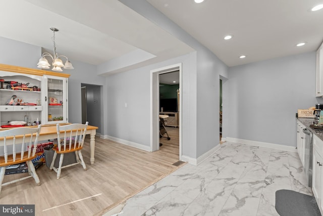 dining space featuring marble finish floor, a notable chandelier, and baseboards