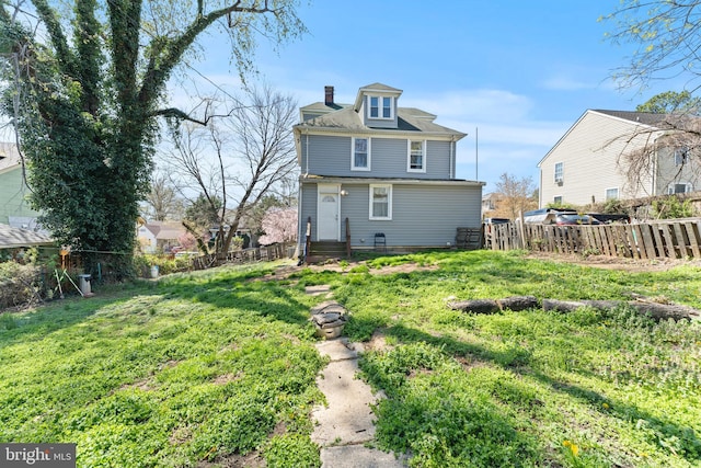 back of house featuring a chimney, fence, and a yard