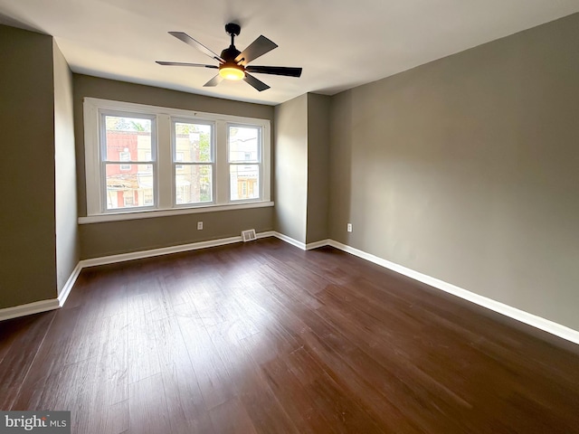 empty room with dark wood-style floors, ceiling fan, and baseboards