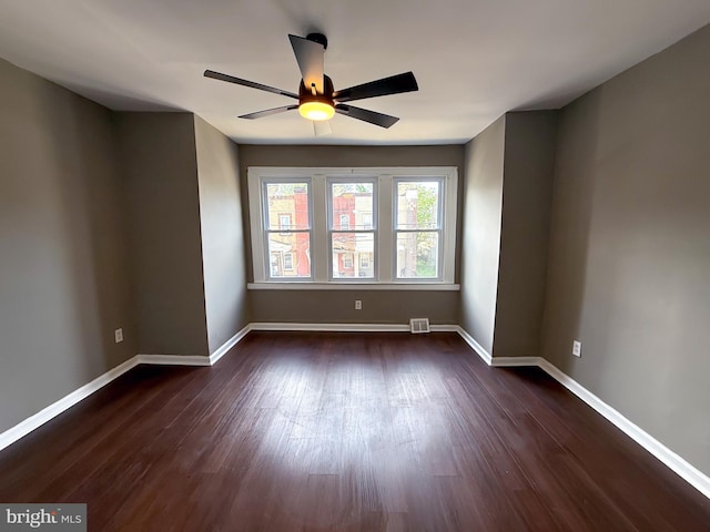 spare room with dark wood-style flooring, ceiling fan, and baseboards