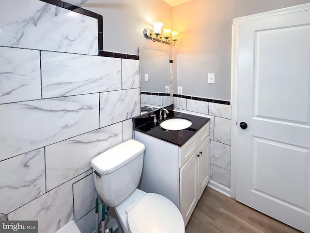 bathroom with tile walls, wood finished floors, vanity, toilet, and a chandelier