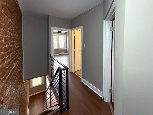 hallway with an upstairs landing, dark wood finished floors, and baseboards