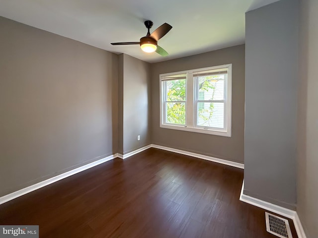 empty room with dark wood-type flooring, baseboards, and a ceiling fan