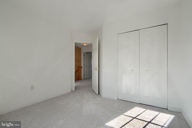 unfurnished bedroom with light colored carpet and a closet