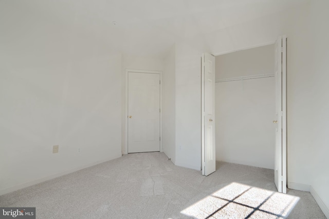 unfurnished bedroom featuring light colored carpet and a closet