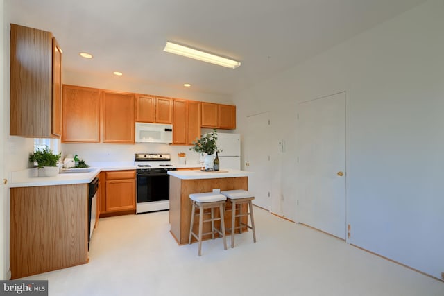 kitchen featuring a kitchen bar, a center island, recessed lighting, white appliances, and light countertops