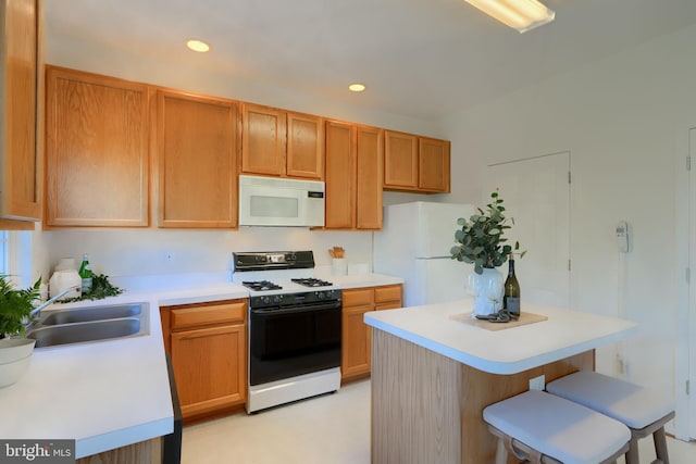 kitchen featuring white appliances, a kitchen island, light countertops, and a sink