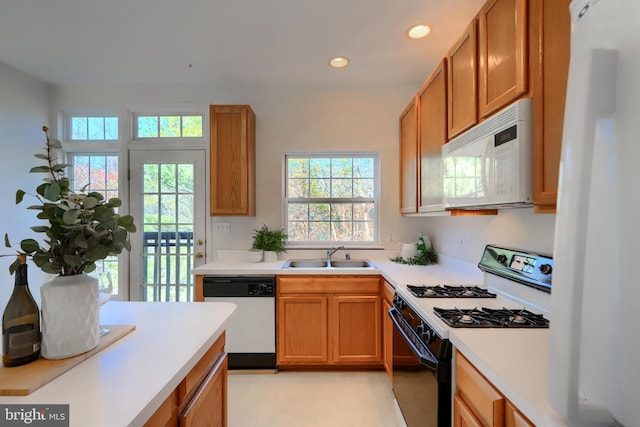 kitchen with white microwave, gas range, dishwashing machine, fridge, and a sink