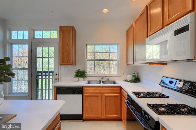 kitchen featuring brown cabinets, a sink, recessed lighting, white appliances, and light countertops