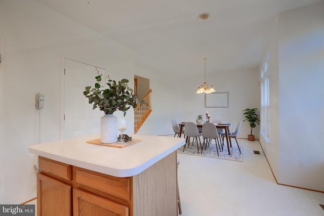 kitchen with a notable chandelier, a kitchen island, light countertops, and visible vents