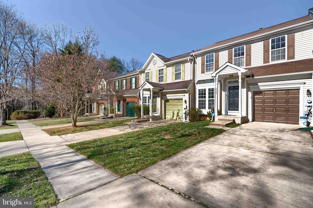 view of property with an attached garage, concrete driveway, and a front yard