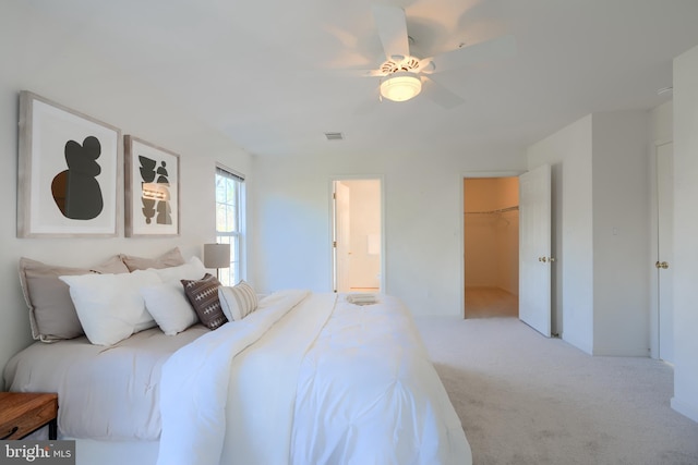 bedroom featuring visible vents, a walk in closet, a closet, carpet, and ceiling fan