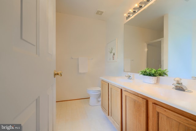full bath with visible vents, double vanity, a stall shower, a sink, and toilet