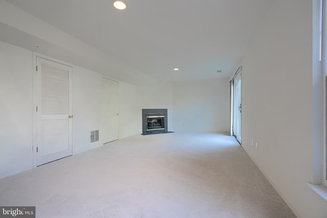 unfurnished living room with recessed lighting, visible vents, a fireplace with flush hearth, and carpet flooring
