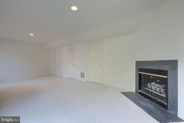 unfurnished living room featuring recessed lighting, visible vents, a fireplace with flush hearth, and carpet flooring