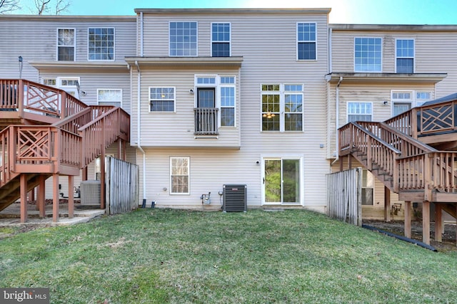 rear view of property featuring cooling unit, a yard, and stairway