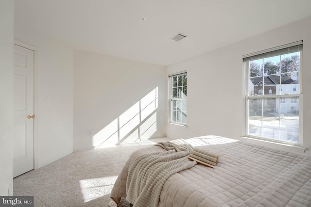 carpeted bedroom featuring visible vents