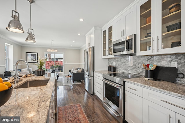 kitchen with ornamental molding, a sink, white cabinetry, stainless steel appliances, and tasteful backsplash
