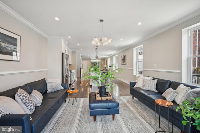 living room with light wood-type flooring, a chandelier, ornamental molding, and recessed lighting