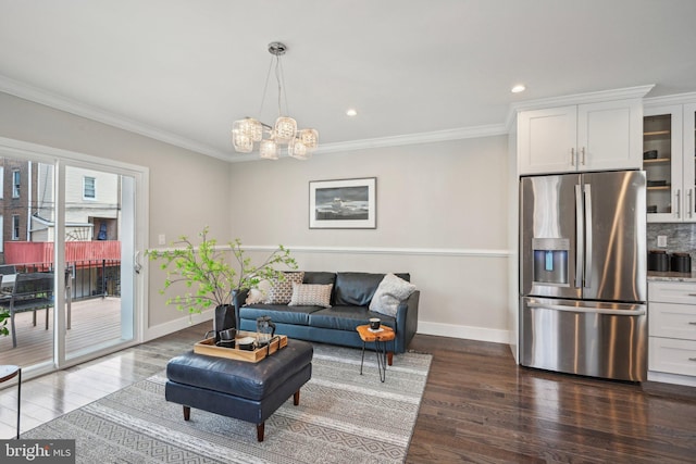 living room featuring a chandelier, ornamental molding, baseboards, and dark wood finished floors