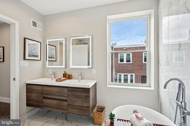 full bathroom with a sink, a soaking tub, marble finish floor, and visible vents