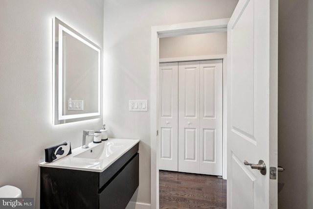 bathroom with toilet, vanity, and wood finished floors