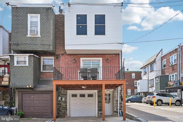 townhome / multi-family property featuring a balcony, brick siding, heating fuel, a garage, and stone siding