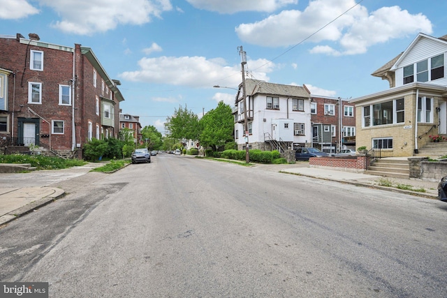 view of street featuring street lights, curbs, sidewalks, and a residential view