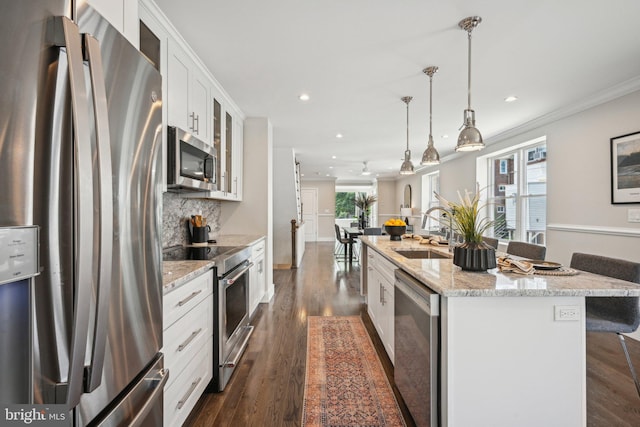 kitchen with a sink, stainless steel appliances, a kitchen island with sink, backsplash, and white cabinets
