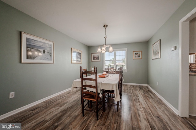 dining space featuring baseboards, a chandelier, and dark wood-style floors