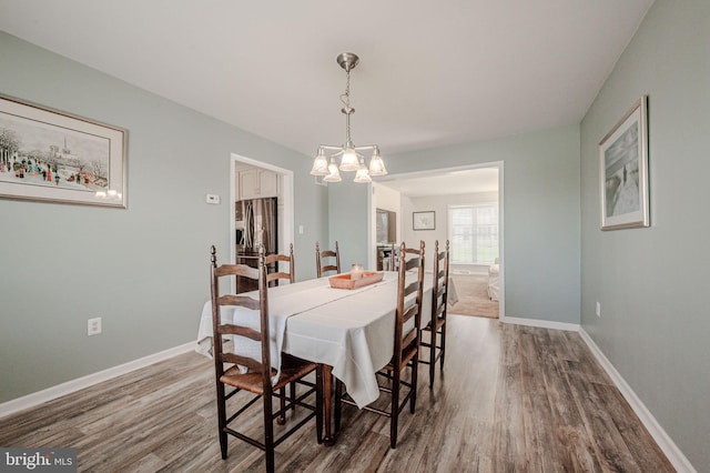 dining area with an inviting chandelier, baseboards, and wood finished floors