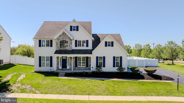 view of front of home featuring fence, a porch, a front lawn, and stone siding