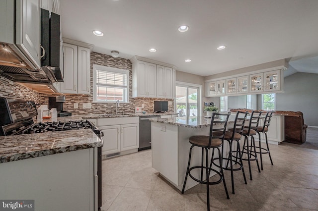 kitchen featuring decorative backsplash, a kitchen island, light stone countertops, a breakfast bar, and stainless steel appliances