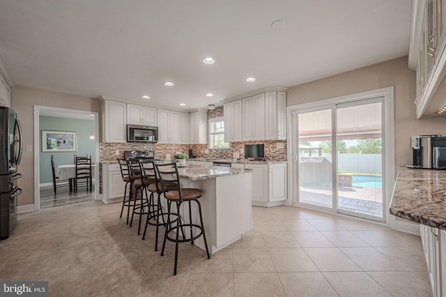 kitchen with a breakfast bar area, appliances with stainless steel finishes, tasteful backsplash, a sink, and recessed lighting