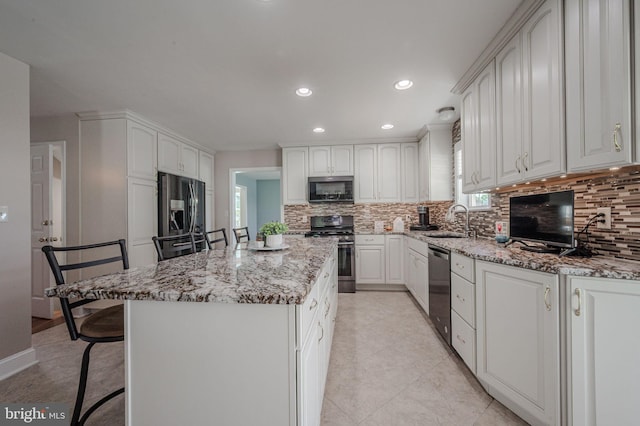 kitchen with stainless steel appliances, light stone countertops, a sink, and tasteful backsplash