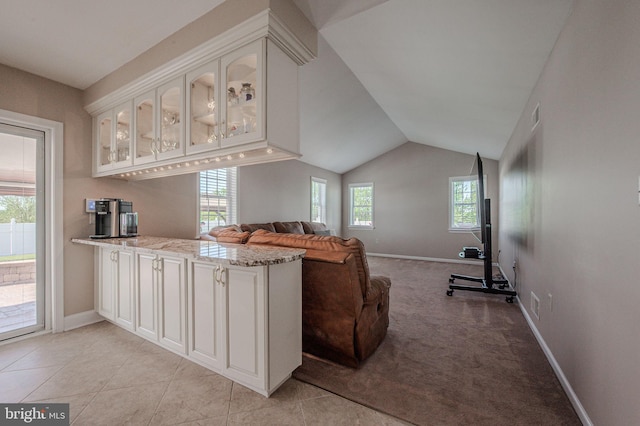 interior space featuring white cabinets, a peninsula, plenty of natural light, and glass insert cabinets