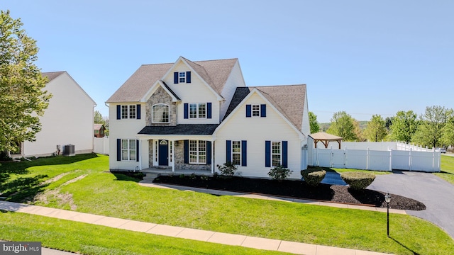 view of front of home featuring fence, covered porch, a front yard, cooling unit, and roof with shingles