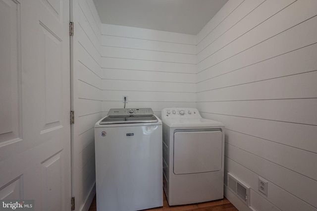 washroom with wooden walls, laundry area, and washing machine and clothes dryer