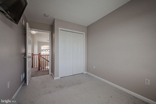 unfurnished bedroom with visible vents, baseboards, a closet, and light carpet