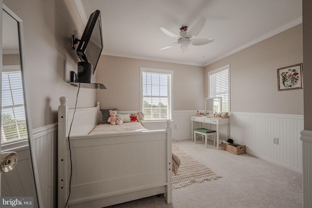 bedroom featuring a ceiling fan, ornamental molding, carpet, and wainscoting