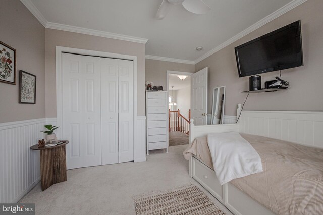 bedroom with crown molding, carpet, and a wainscoted wall