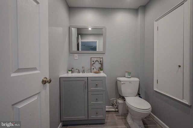 bathroom with toilet, baseboards, and vanity