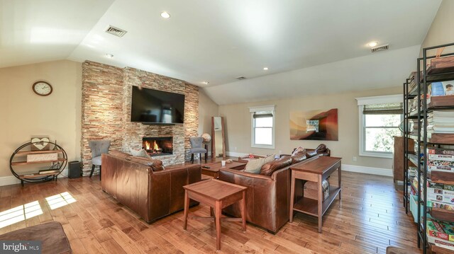 living room with visible vents, a fireplace, and vaulted ceiling