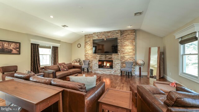 living room featuring visible vents, a fireplace, wood finished floors, and vaulted ceiling