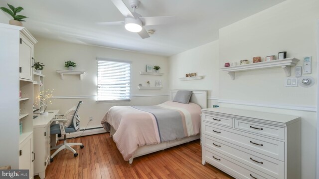 bedroom featuring light wood-style flooring, a ceiling fan, and a baseboard radiator