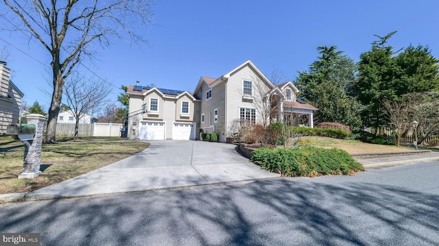view of front facade featuring a garage, solar panels, driveway, and fence