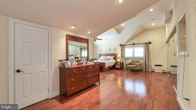 bedroom with lofted ceiling, a wall mounted AC, wood finished floors, recessed lighting, and baseboards