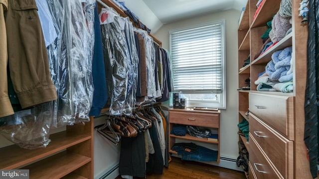 walk in closet with a baseboard heating unit and wood finished floors